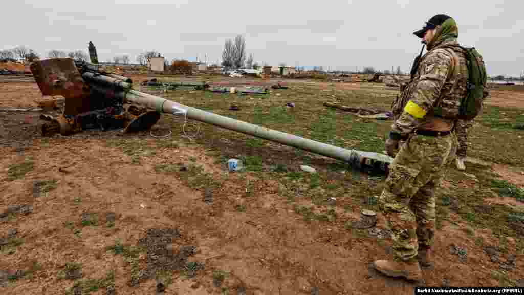 Военный ВСУ смотрит на уничтоженную российскую военную технику недалеко от аэропорта «Херсон» в Чернобаевке, 13 ноября 2022 года