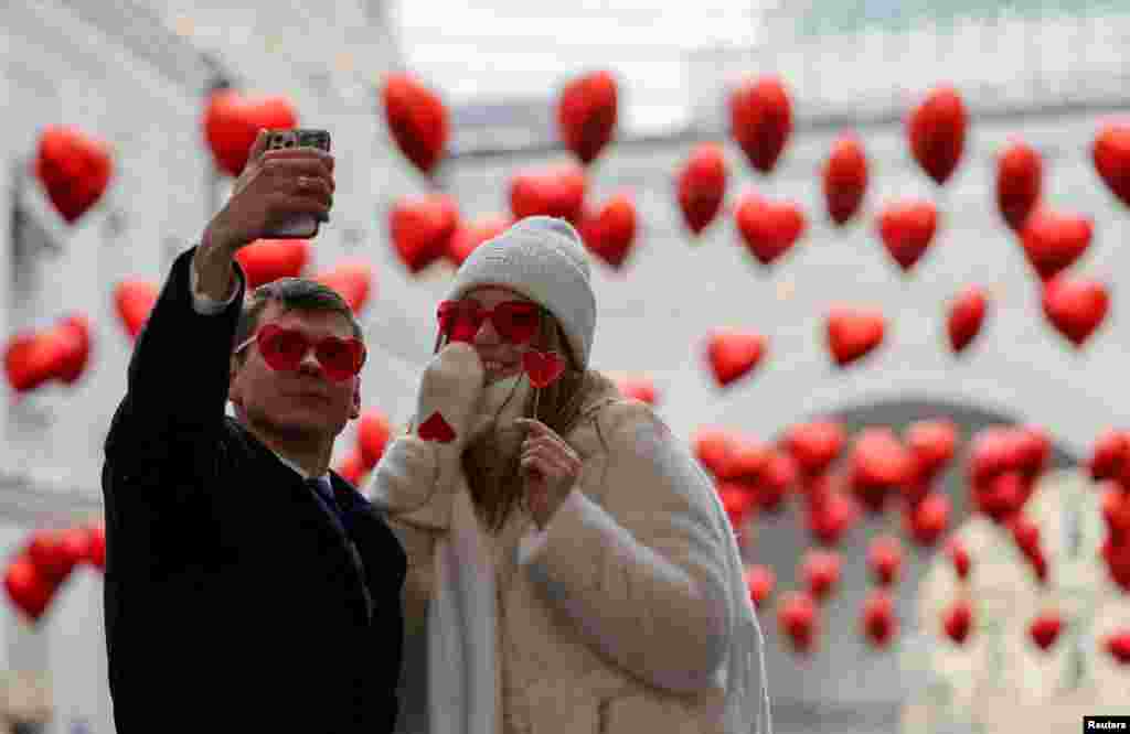 Par pozira za selfie u ukrašenoj ulici na Valentinovo u Moskvi, Rusija, 14. februara 2024. 