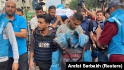 Colegii jurnalistului Mohammed Soboh, ucis în Gaza, pe 10 octombrie, îi cară vesta pătată de sânge.