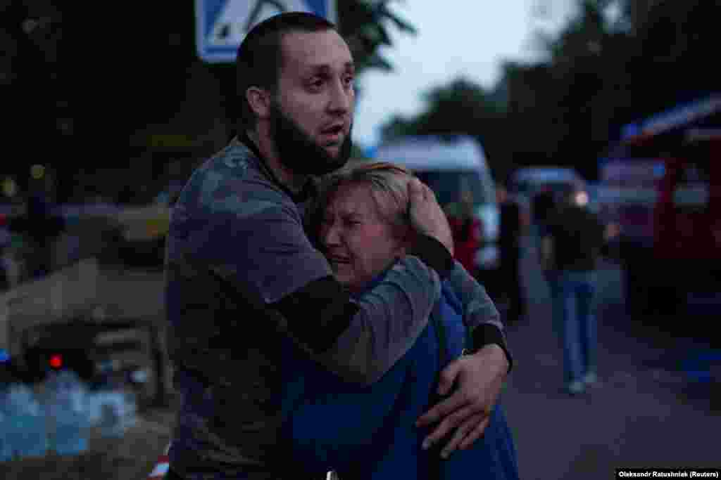 Мужчина утешает женщину на месте сильно пострадавшего от ракетного удара России здания в Краматорске 