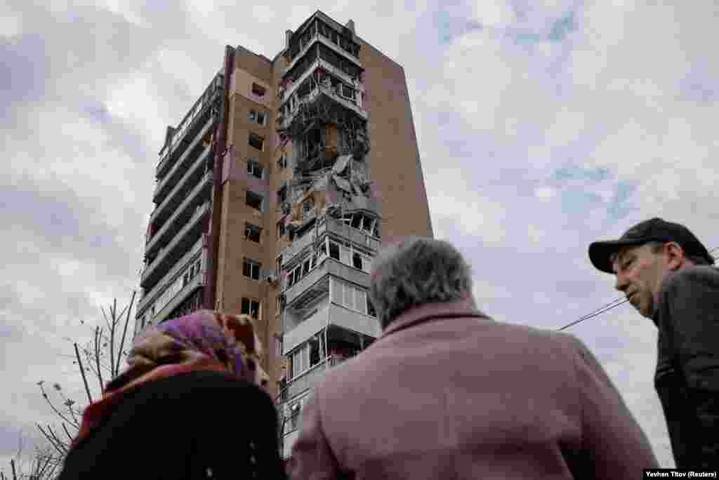 Местные жители стоят перед жилым домом, пострадавшим от удара российского беспилотника, в Харькове, Украина, 4 апреля 2024 года. 