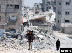 Palestinci prolaze pored kuća koje su uništene u izraelskom napadu, Kan Junis, jug Pojasa Gaze, 22. maja 2024.