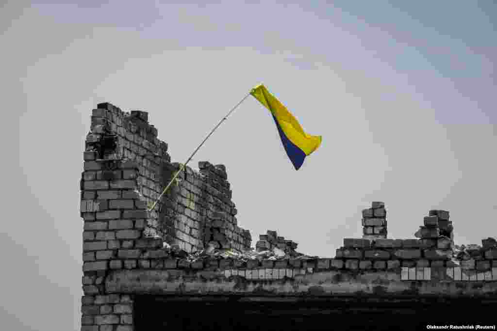 Украинский флаг над разрушенным домом в недавно освобождённом селе Нескучное в Донецкой области, 13 июня 2023 года. Журналистам разрешили войти в село, чтобы продемонстрировать им успехи, которых добились украинские силы в своём контрнаступлении против российских войск