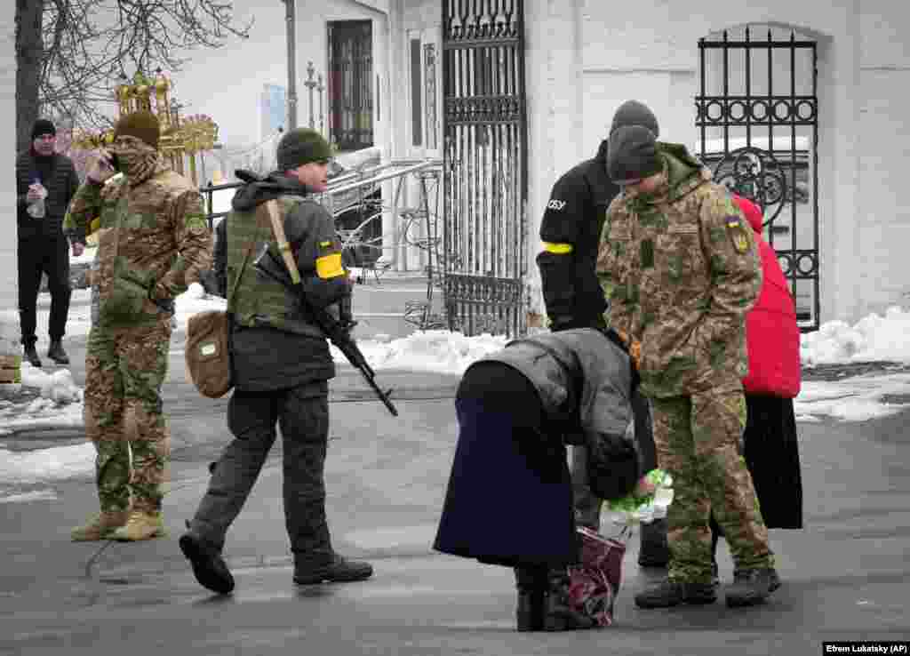 Украинские силовики осматривают содержимое сумки женщины на территории лавры, 22 ноября 2022 года. Власти провели обыск в монастырском комплексе вскоре после того, как 12 ноября 2022 года в Сети появилось видео, на котором верующие внутри храма поют песню во славу России, заканчивающуюся строчкой с текстом: «Звон плывёт, плывёт над Россией, пробуждается матушка-Русь» 