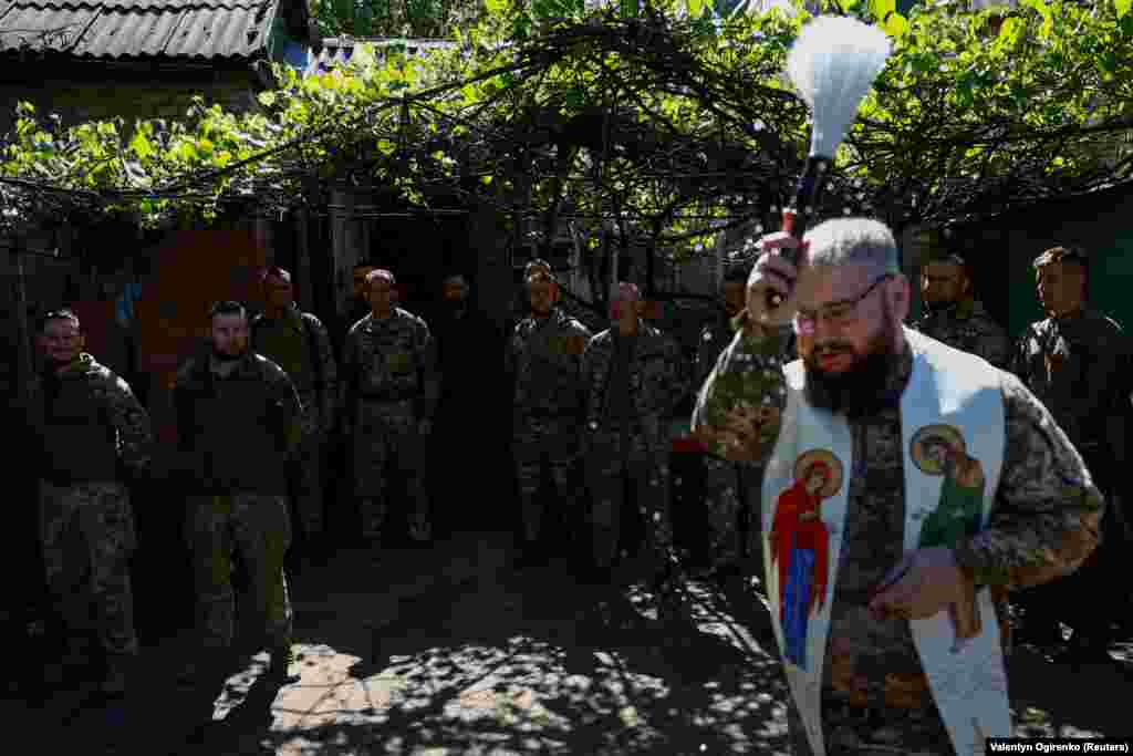 Військовий капелан Олександр Карапетян окроплює свяченою водою військовослужбовців 93-ї окремої механізованої бригади «Холодний Яр» під час Великодного богослужіння поблизу лінії фронту. Донецька область, 5 травня 2024 року 