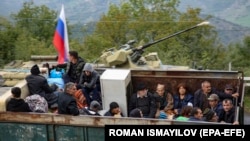 Jermenske izbeglice sjede u zadnjem delu kamiona na kontrolnom punktu Lačin, koji kontrolišu ruski mirovnjaci i azerbejdžanska granična straža, dok čekaju da pređu u Jermeniju, 27. septembar 2023. 