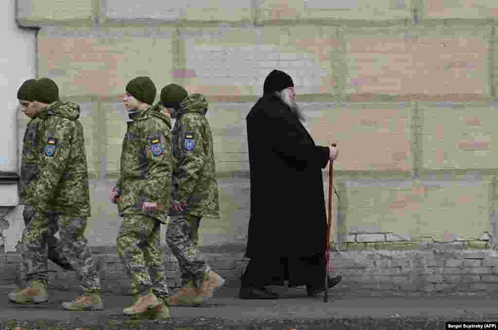 Украинские военные и православный священник в Киево-Печерской лавре, 14 марта 2023 года. Напряжённость вокруг монастыря возрастает. Власти установили 29 марта крайним сроком, до которого священнослужители должны покинуть территорию лавры. Монахи, которых вместе с послушниками в лавре сейчас около 200 человек, выселяться отказываются