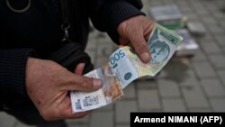 Ulični prodavac drži dinare u Gračanici u centralnom delu Kosova, 1. mart 2024.