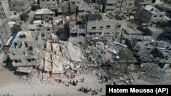 Palestinci stoje uz zgradu uništenu u zračnom napadu u kampu Nuseirat, u pojasu Gaze, ponedjeljak, 16. oktobra 2023.
