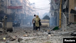 Palestinka gleda dok hoda ulicom punom ruševina u blizini tornja Watan, koji je uništen u izraelskim napadima, u gradu Gazi 8. oktobra 2023.