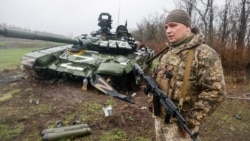 Un soldat ucrainean stă lângă un tanc rusesc T-72 distrus în regiunea Donețk, estul Ucrainei, 13 aprilie 2022