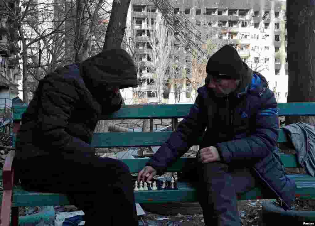Қала тұрғындары аулада шахмат ойнап отыр. 