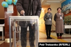 Қазақстан президентін сайлауға дауыс беріп жатқан сайлаушы мен оны сыртынан бақылап тұрған учаскелік комиссия мүшелері. Алматы, 20 қараша 2022 жыл.