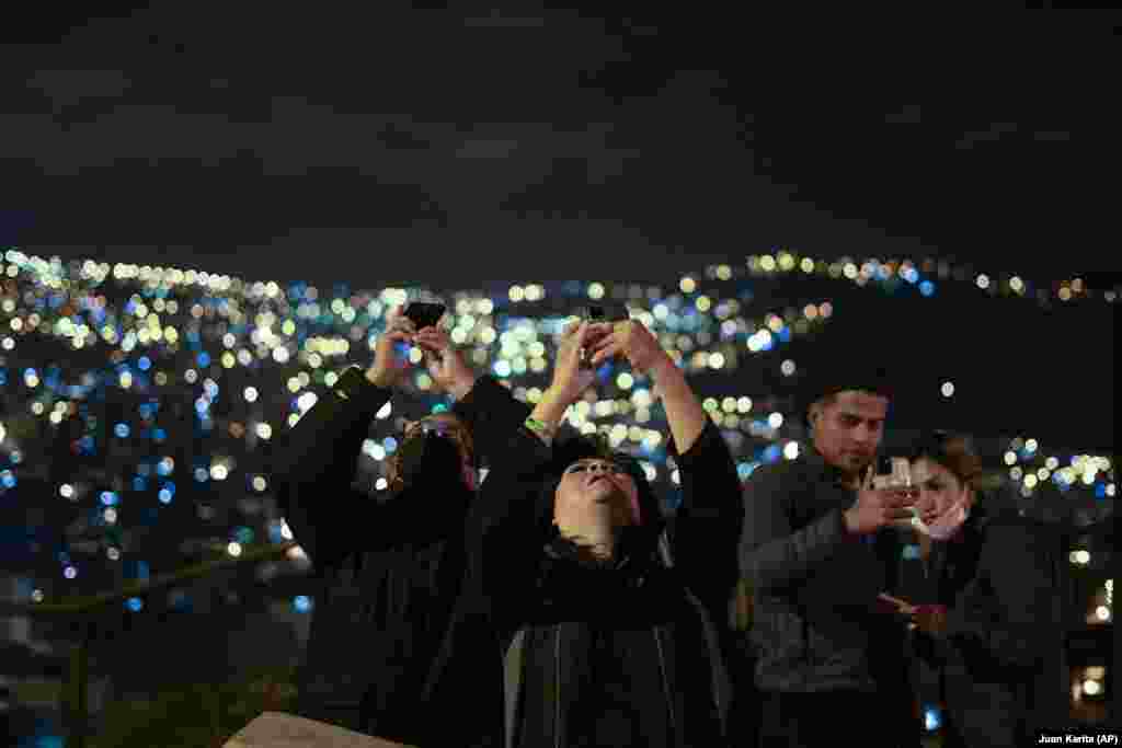 Oamenii fotografiază eclipsa în La Paz, Bolivia, 15 mai 2022. Vizibil cu ochiul liber sau cu ajutorul unui binoclu, fenomenul poate oferi celor pasionaţi posibilitatea de a face „fotografii spectaculoase", atunci când condiţiile atmosferice sunt favorabile. 