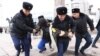 Полицейские задерживают и ведут к автозаку активиста на площади Республики в Алматы. 20 ноября 2022 года