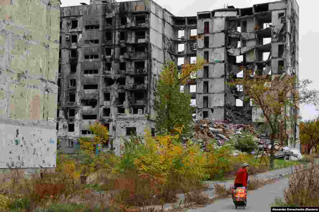 Женщина идет мимо полностью разрушенных российскими бомбардировками и не пригодных к жизни зданий в Мариуполе. 