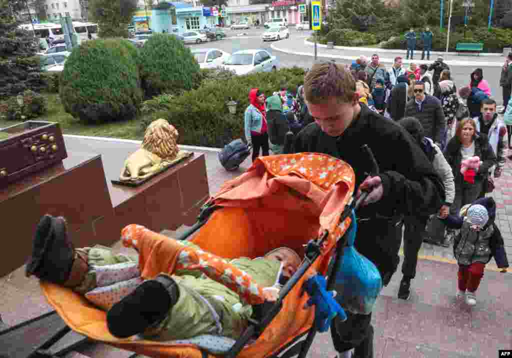 Мужчина несет ребенка в коляске вверх по лестнице Джанкойского железнодорожного вокзала в Крыму 21 октября. По данным российского информационного агентства «Интерфакс», с 18 октября регион покинули около 25 тыс. человек.