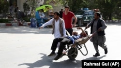 Afghan men carry a wounded man after the second blast in Kabul on April 30
