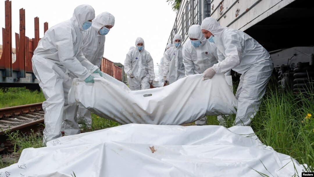 Muncitorii ucraineni transportă cadavrele soldaților ruși uciși în timpul invaziei înainte de a-i pune într-un vagon frigorific la Kiev, pe 13 mai.