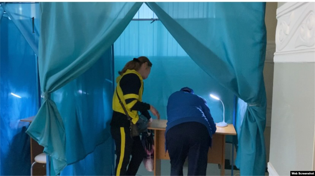 Алматы қаласындағы N529 сайлау учаскесінде бір кабинада дауыс беру бюллетеніне белгі қойып жатқан адамдар. 5 маусым 2022 жыл. 