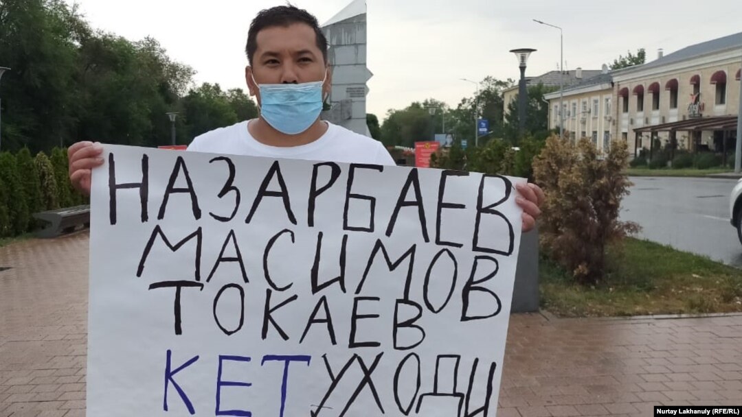 Житель Алматы Ерболат Туркеев у монумента «Заря Независимости» с плакатом «Назарбаев, Токаев, Масимов, кет, уходи!». Алматы, 18 августа 2020 года.