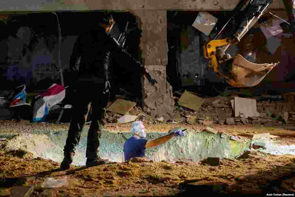 Israeli emergency workers inspect the impact crater of an Iranian rocket after it hit a school building in the center of the country. 