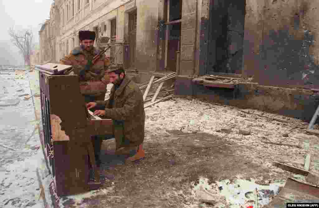 Боец сопротивления играет на пианино в центре Грозного. Музыкальный инструмент, скорее всего, был подготовлен к вывозу из республики. Многие дома в первые дни войны были разграблены федеральными войсками, а потом подвергнуты бомбардировке или сожжению. 22 декабря 1995 года.