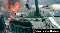 Мужчина с флагом Чехословакии у советского танка возле здания радиостанции в центре Праги, где во время подавления Пражской весны погибли 17 человек, 1968 год.