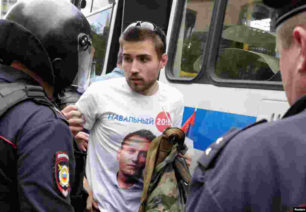 Мәскеу полициясы Алексей Навальныйдың президент сайлауы науқанына қатысы бар символикасының суреті бар киім киген адамды ұстап жатыр. 