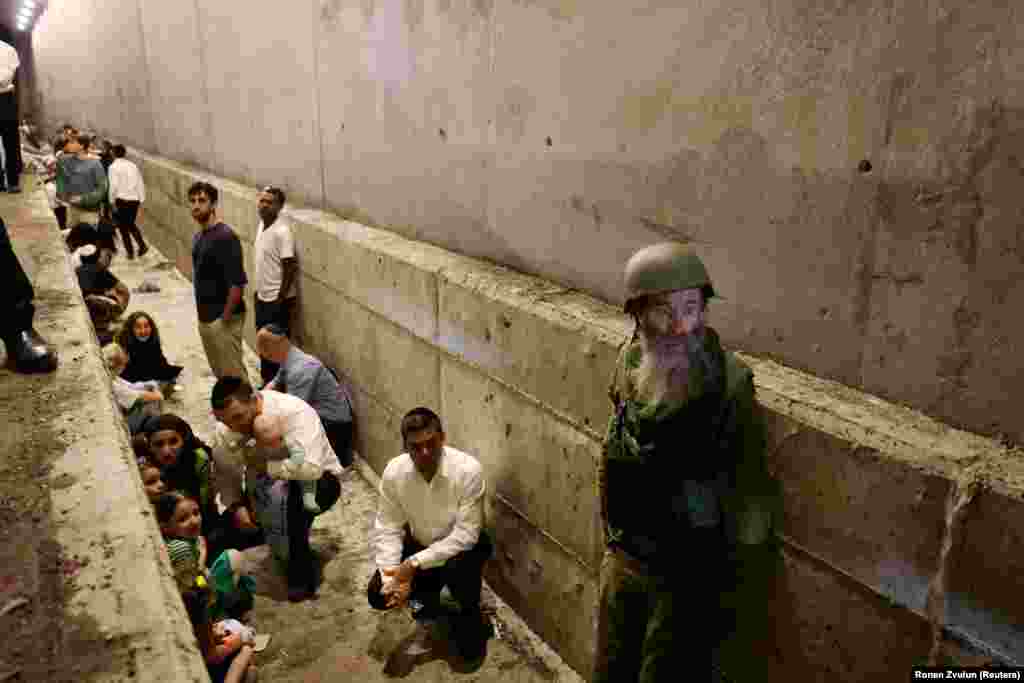 Israelis shelter in a ditch amid the October 1 attack. Two Israeli air bases were targeted in the strikes and some missiles landed near the headquarters of the Mossad spy agency in Tel Aviv. 
