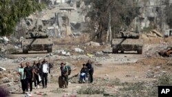 Un grup de palestinieni se evacuează din nordul Fâșiei Gaza, cu tancuri israeliene în urma lor, pe drumul Salah al-Din, pe 24 noiembrie 2023. Agențiile umanitare trag un nou semnal de alarmă cu privire la situația umanitară.