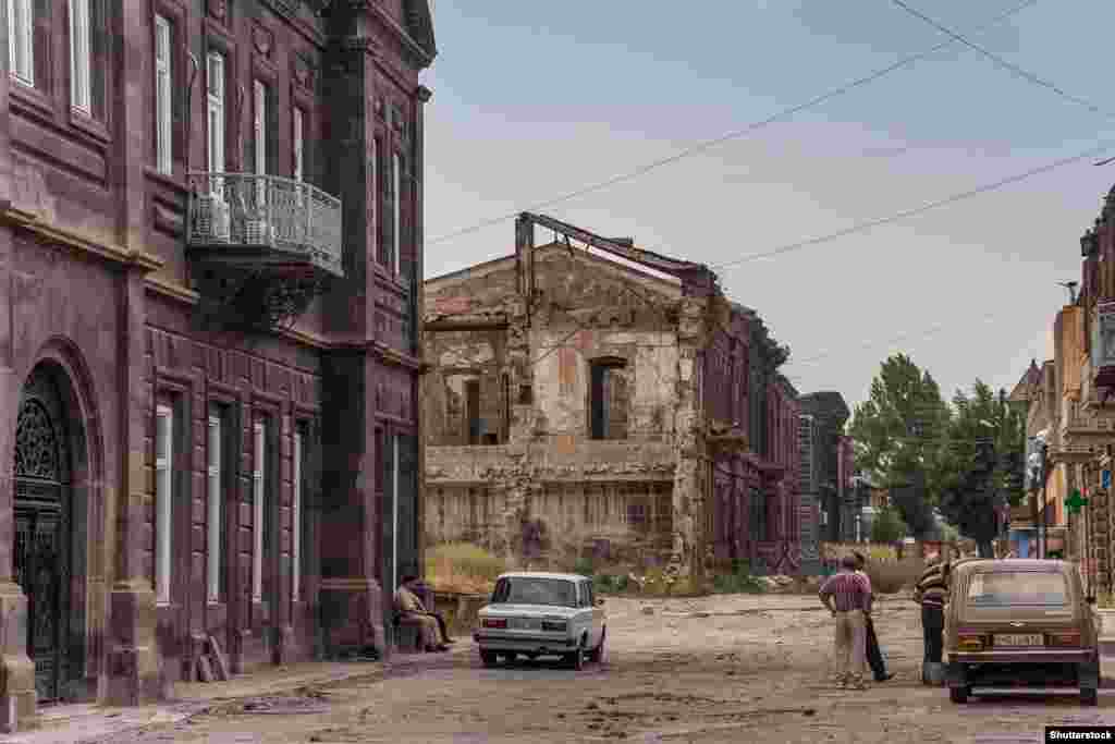Разрушенное землетрясением здание в Гюмри в 2013 году. Со времен трагедии, которая уничтожила и большинство городских предприятий, население города сократилось почти вдвое. Для переживших землетрясение, как и в целом для многих армян, более привлекательной выглядит работа в России. Как сказал один из местных жителей в 2013 году, "безработица и бедность еще страшнее", чем угроза нового землетрясения. 