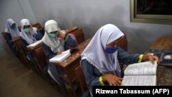 د کراچۍ د یوه ښوونځي په ټولګي کې ماشومانې کتاب لولي - انځور له ارشیفه. 
