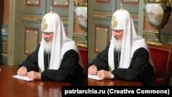 Патріарх РПЦ Кирило зі своїм дорогим годинником, який на фотографії після скандалу заретушували, однак залишилось його віддзеркалення на столі