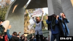 Iranian students clash with riot police during an anti-government protest around the University of Tehran on December 30