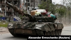 Российские военные на танке в городе Попасная в Луганской области с бытовыми вещами, которые, по словам вынужденной переселенки Алины Коренюк, были похищены из ее дома, 26 мая 2022 года 