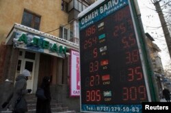 Люди проходят мимо пункта обмена валют. Алматы, 11 февраля 2014 года.