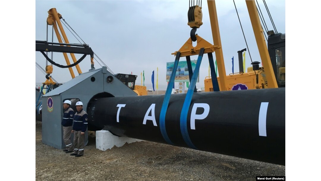 Turkmen workers stand near a gas pipe during the February 23 launching ceremony for construction work on the TAPI pipeline.