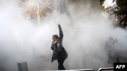 An Iranian woman raises her fist amid the smoke of tear gas at the University of Tehran during a protest driven by anger over economic problems in the capital on December 30.
