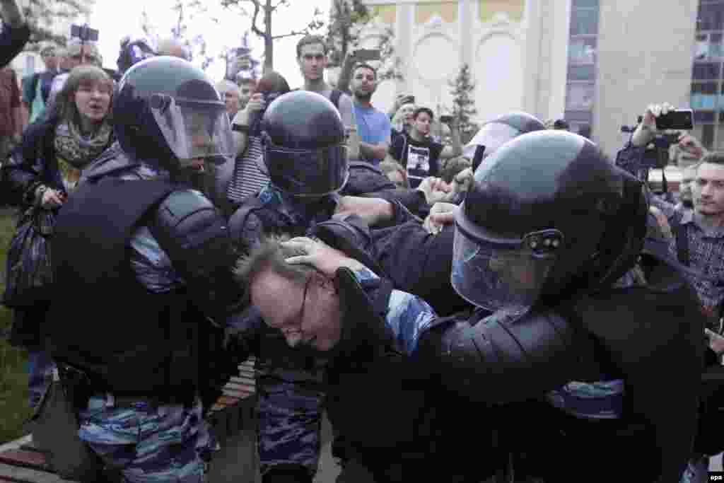Мәскеудегі наразылық шарасына қатысқан азаматты ұстап жатқан полиция жасағы. 