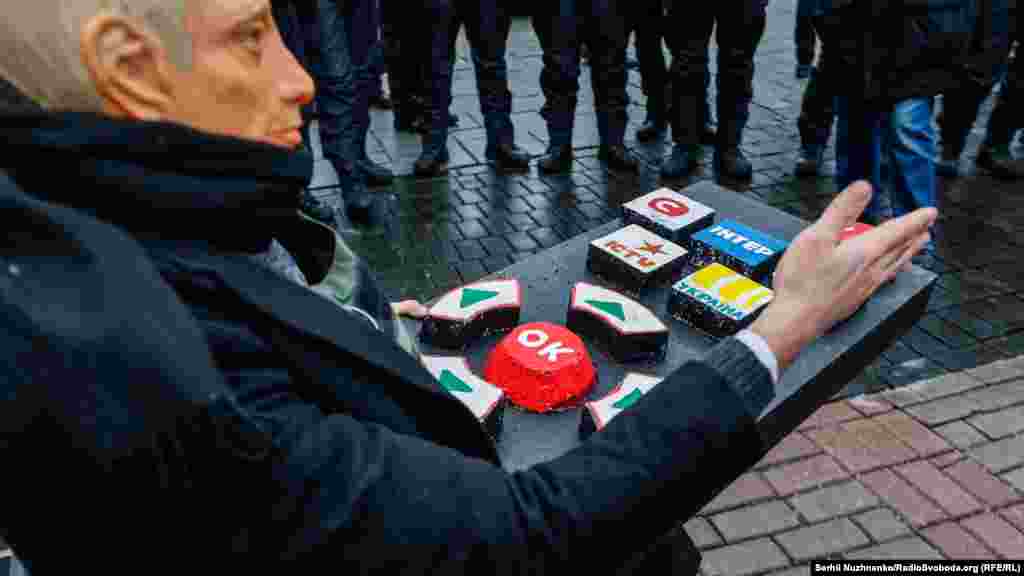 Учасники акції провели перфоманс – активіст, одягнений у маску Путіна, сидів на стільці з великим пультом, де були написані назви українських телеканалів