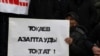 Мужчина держит плакат с надписью: «Токаев, останови пытки!» — на траурном митинге в память о жертвах Кровавого января. Алматы, 13 февраля 2022 года