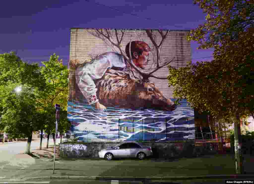 «Переправа», автор – австралійський художник Fintan Magee. Спалах вуличного мистецтва в Києві частково є результатом роботи місцевої молоді, зокрема, об’єднань Mural Social Club і Art United Us, які організовують приїзд іноземних художників для відвідин і роботи в Україні (вулиця Волоська, 19/22)