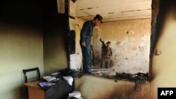 FILE: An Afghan National Army (ANA) soldiers and a policeman walk on the floor of a room at a courthouse in Farah province.