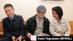 Поэт и гражданский активист Кенжебек Абишев (в центре) в зале судебного заседания Алмалинского районного суда изучает ходатайство следователя Толганай Ержановой о продлении ему ареста. Алматы, 19 апреля 2018 года.